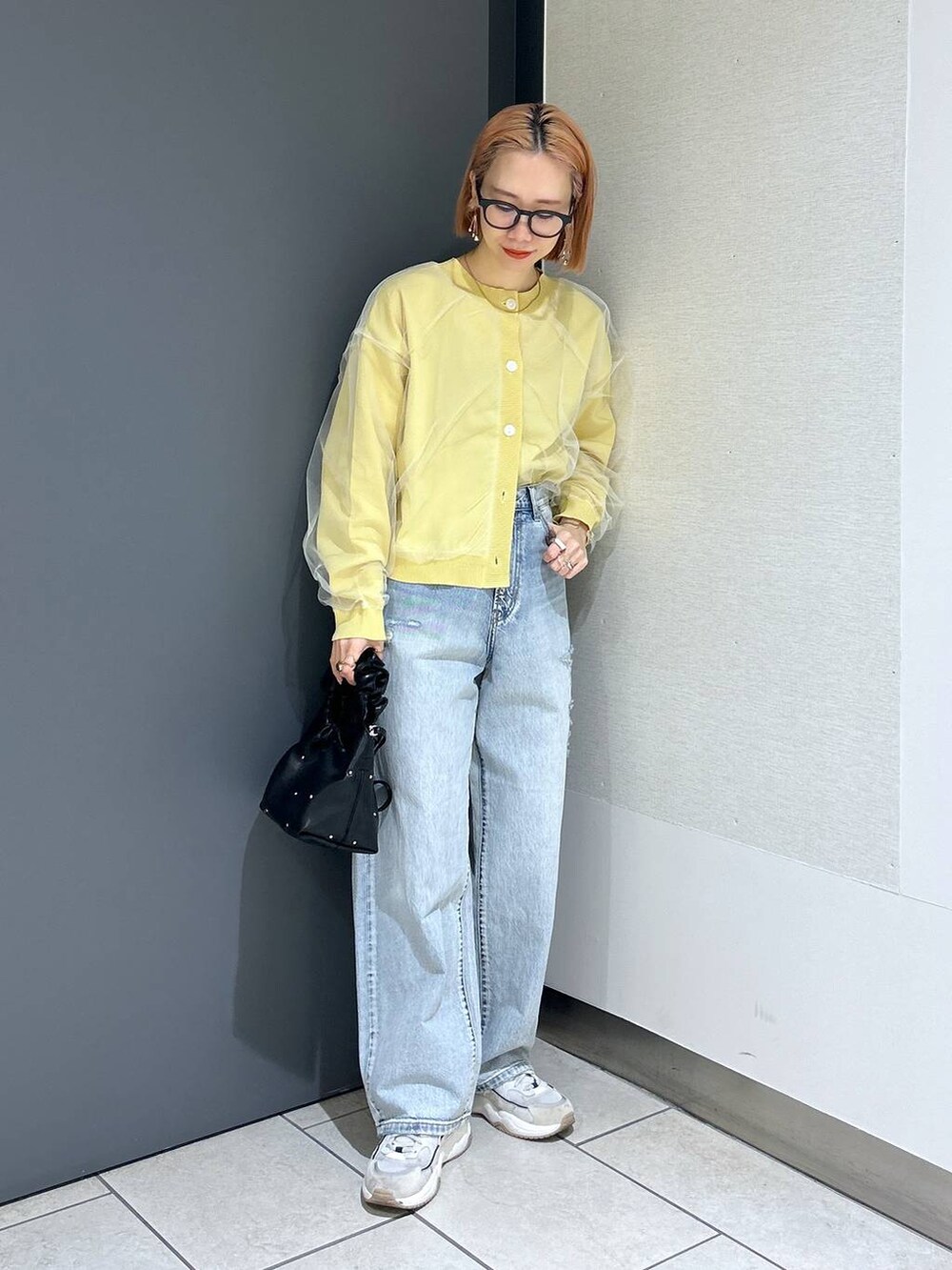 ブラック系のハンドバッグ、イエロー系のニット/セーター、ブラック系のTシャツ/カットソーを着用したレディースの春コーディネートの8枚目の写真