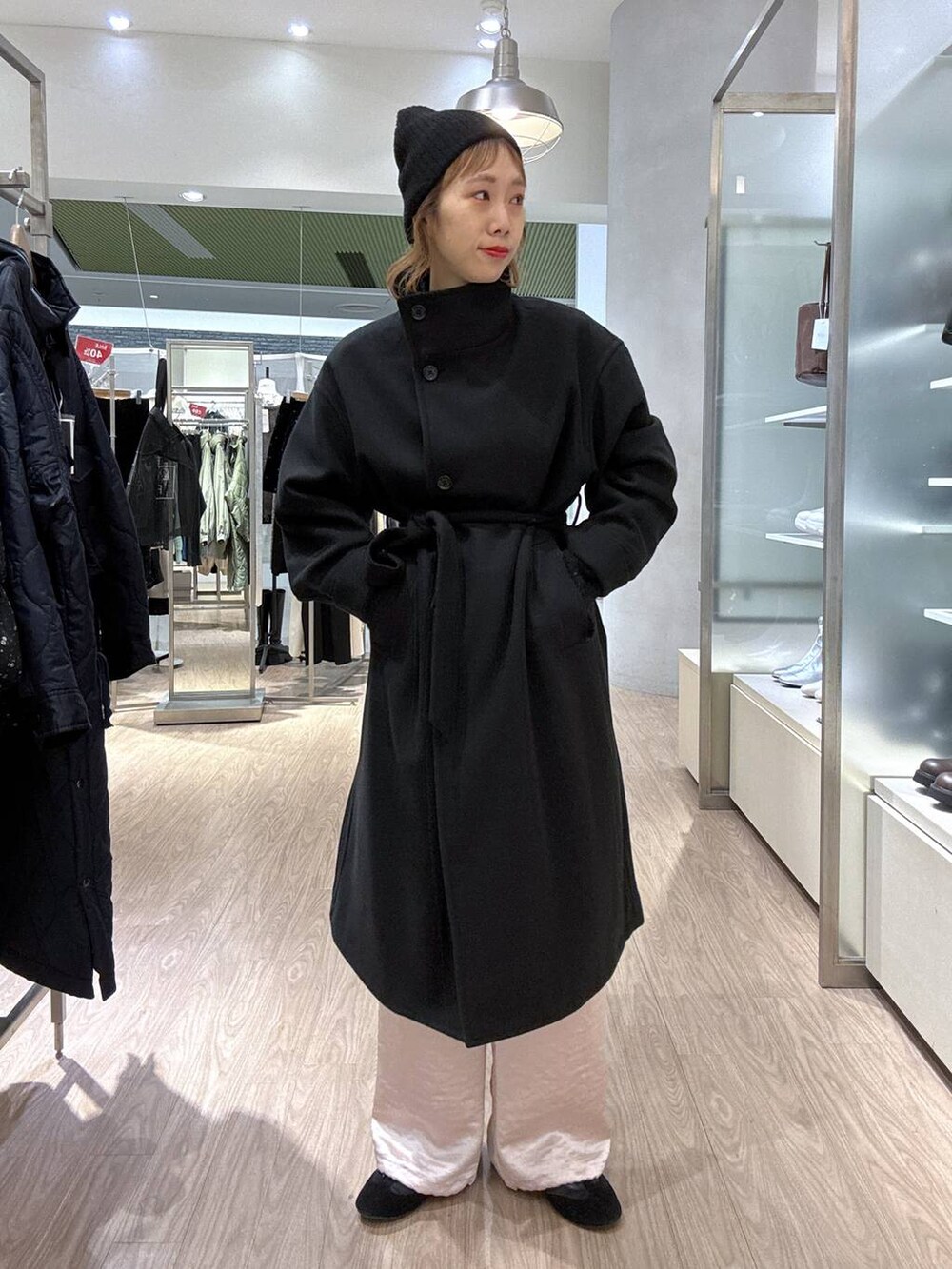 ブラック系のステンカラーコート、ピンク系のカーゴパンツ、ブラック系のニット/セーターを着用したレディースの冬コーディネートの7枚目の写真