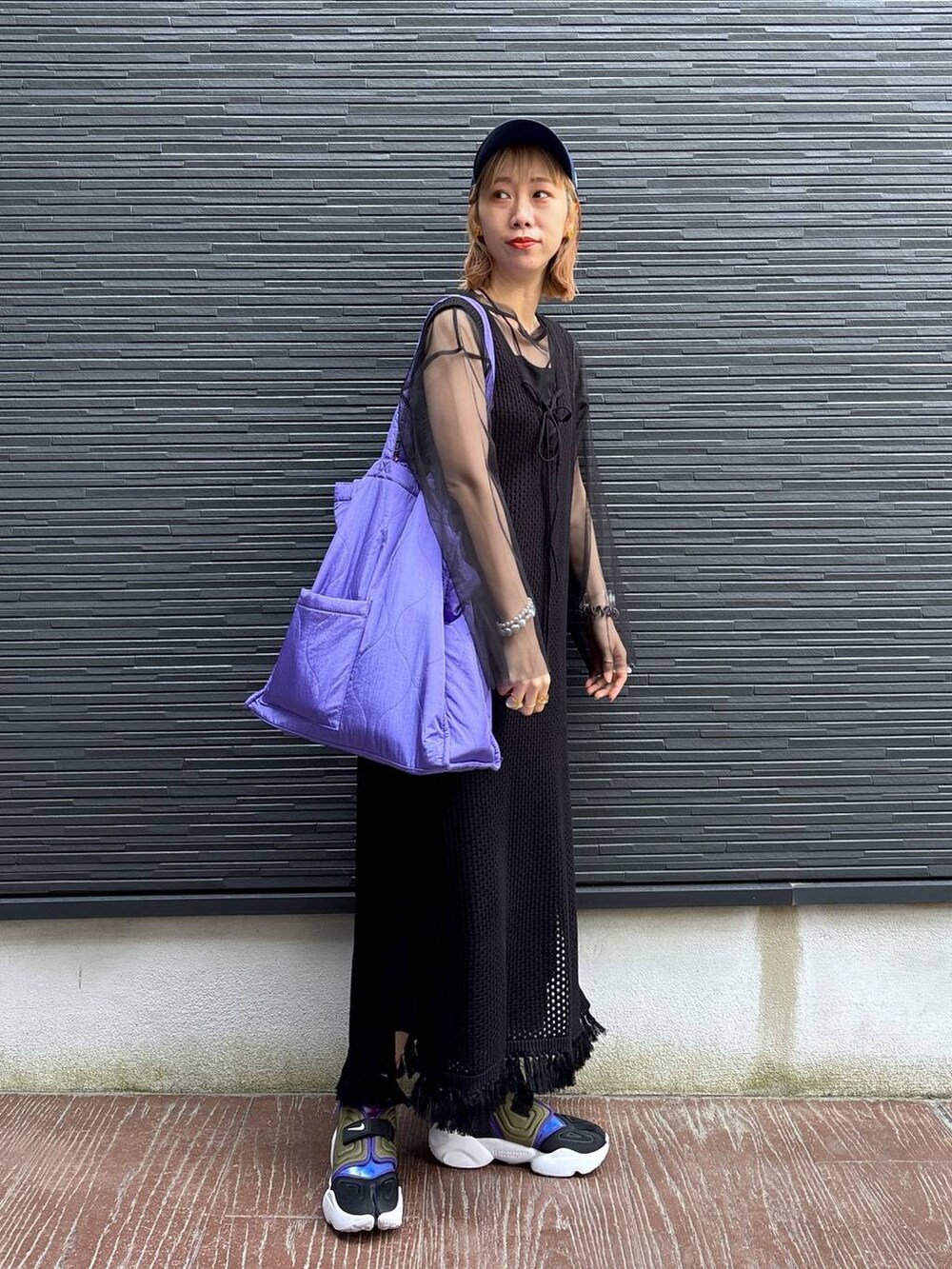 ブラック系のワンピース、パープル系のショルダーバッグ、ブラック系のスカートを着用したレディースの春コーディネートの6枚目の写真