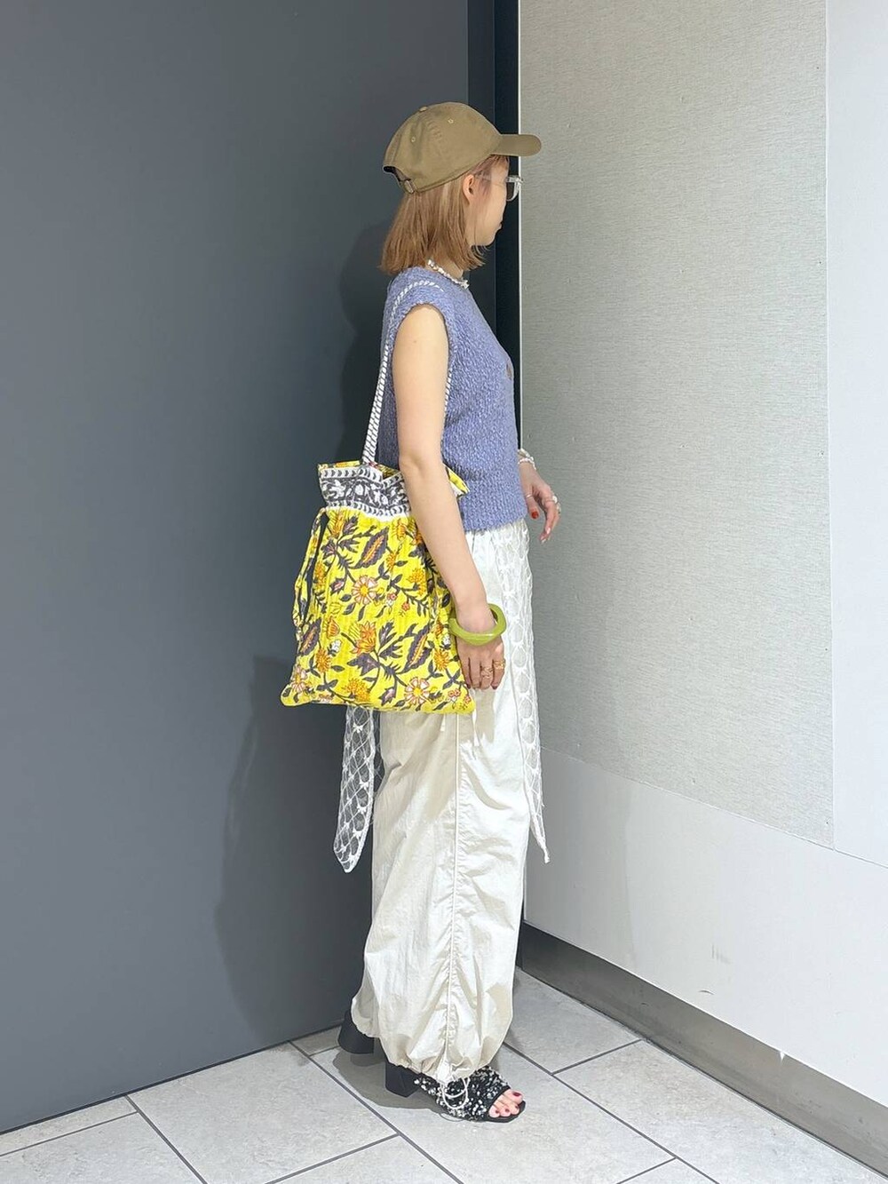 イエロー系のトートバッグ、シルバー系のサンダル、ホワイト系のその他パンツを着用したレディースの夏コーディネートの5枚目の写真