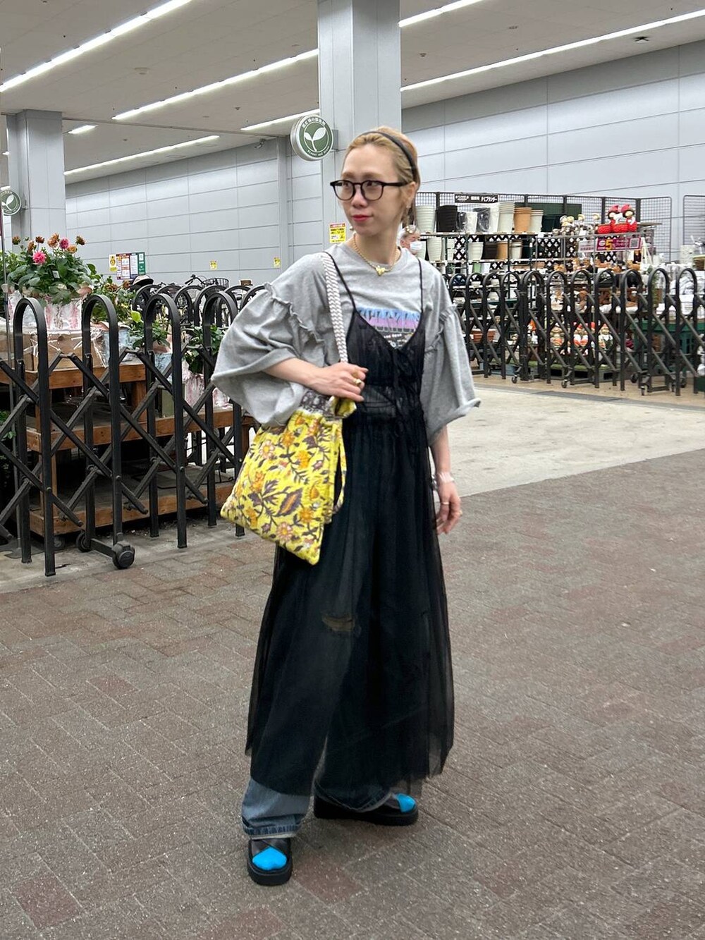 ブラック系のサンダル、ブルー系のデニムパンツ、イエロー系のトートバッグを着用したレディースの春コーディネートの2枚目の写真