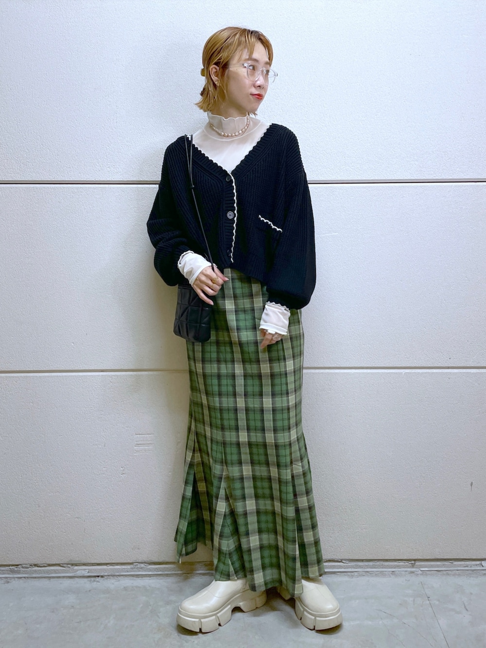 ブラック系のカーディガン/ボレロ、ホワイト系のトップス、グリーン系のスカートを着用したレディースの秋コーディネートの4枚目の写真