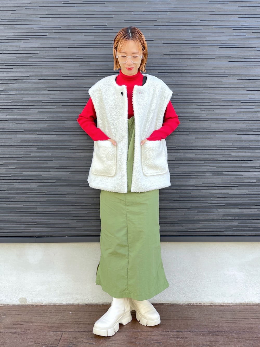 レッド系のニット/セーター、ブラック系のジャケット/アウター、ホワイト系のブーツを着用したレディースの冬コーディネートの5枚目の写真