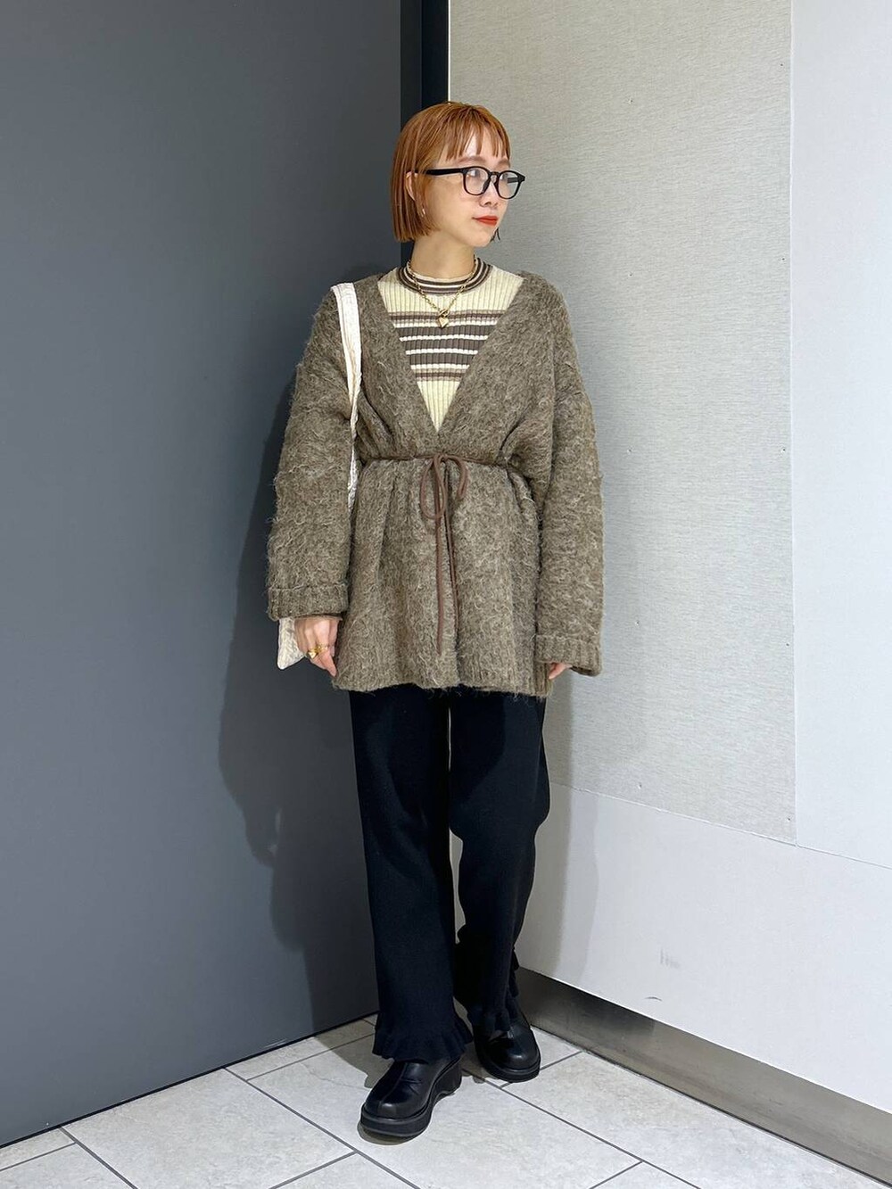 ホワイト系のトートバッグ、ブラック系のその他パンツ、ブラック系のブーツを着用したレディースの秋コーディネートの2枚目の写真