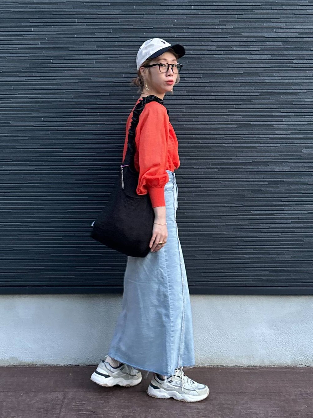 ブラック系のトートバッグ、オレンジ系のカーディガン/ボレロ、ブルー系のスカートを着用したレディースの夏コーディネートの3枚目の写真