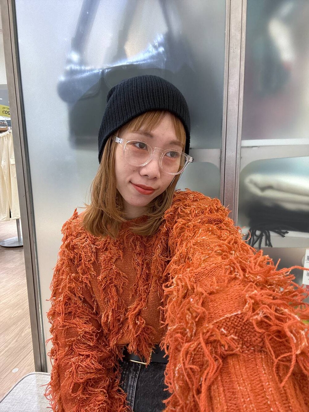 オレンジ系のカーディガン/ボレロ、ブラック系のスニーカー、ブラック系のベルトを着用したレディースの冬コーディネートの7枚目の写真