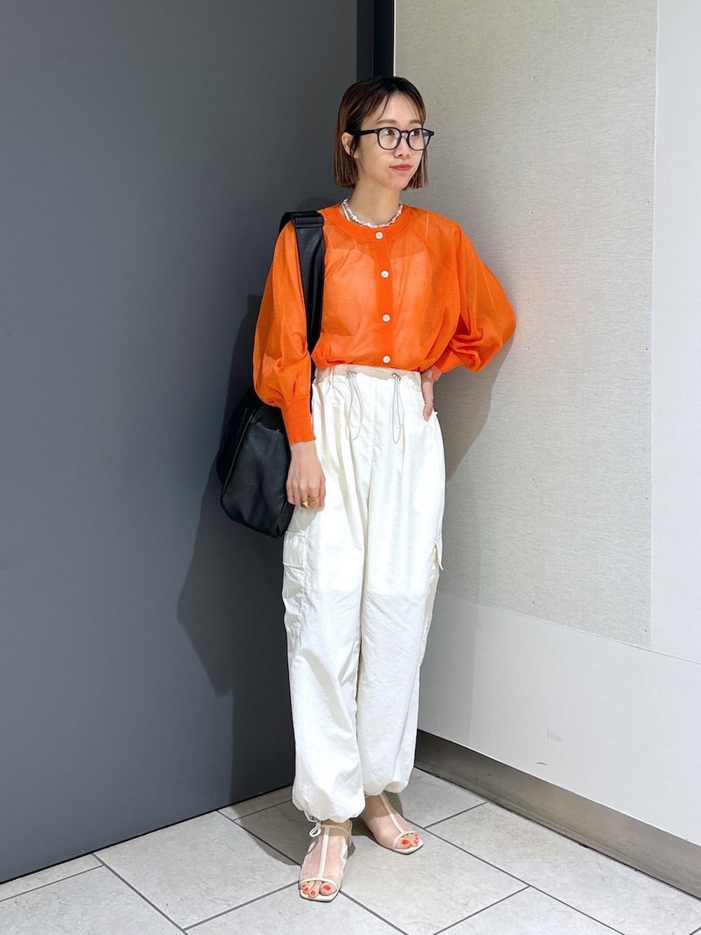 オレンジ系のカーディガン/ボレロ、ホワイト系のトップス、ホワイト系のその他パンツを着用したレディースの春コーディネートの6枚目の写真