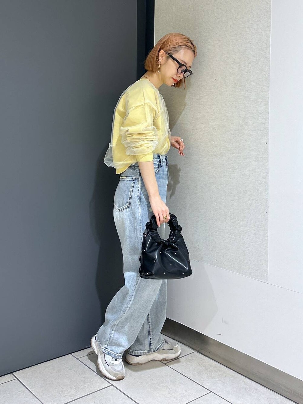 ブラック系のハンドバッグ、イエロー系のニット/セーター、ブラック系のTシャツ/カットソーを着用したレディースの春コーディネートの7枚目の写真