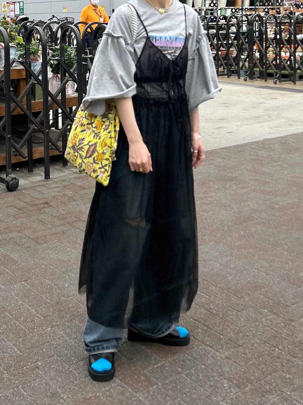 ブラック系のサンダル、ブルー系のデニムパンツ、イエロー系のトートバッグを着用したレディースの春コーディネートの7枚目の写真