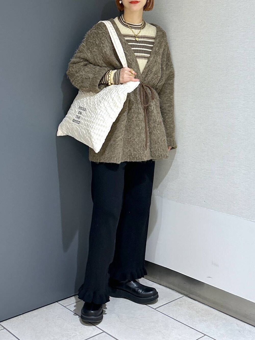 ホワイト系のトートバッグ、ブラック系のその他パンツ、ブラック系のブーツを着用したレディースの秋コーディネートの6枚目の写真