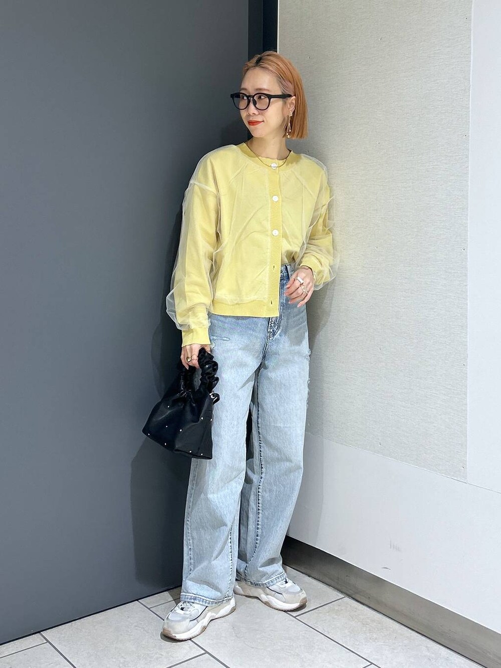 ブラック系のハンドバッグ、イエロー系のニット/セーター、ブラック系のTシャツ/カットソーを着用したレディースの春コーディネートの4枚目の写真