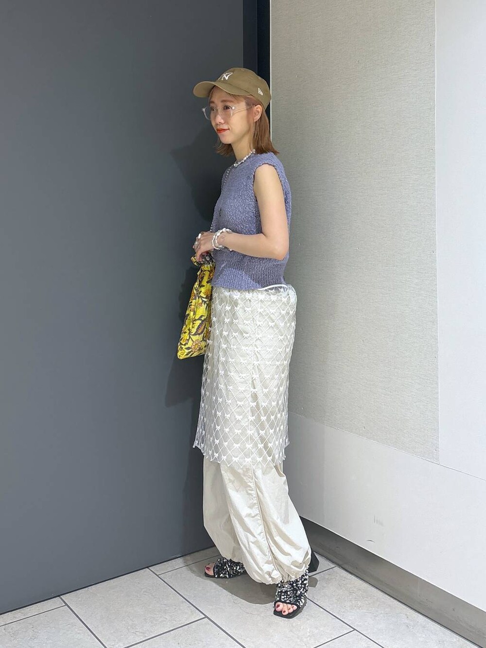 イエロー系のトートバッグ、シルバー系のサンダル、ホワイト系のその他パンツを着用したレディースの夏コーディネートの3枚目の写真