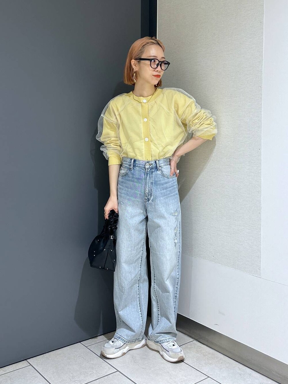 ブラック系のハンドバッグ、イエロー系のニット/セーター、ブラック系のTシャツ/カットソーを着用したレディースの春コーディネートの9枚目の写真