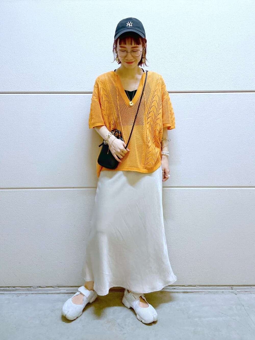 ブラック系のTシャツ/カットソー、オレンジ系のニット/セーター、ブラック系のスカートを着用したレディースの春コーディネートの5枚目の写真