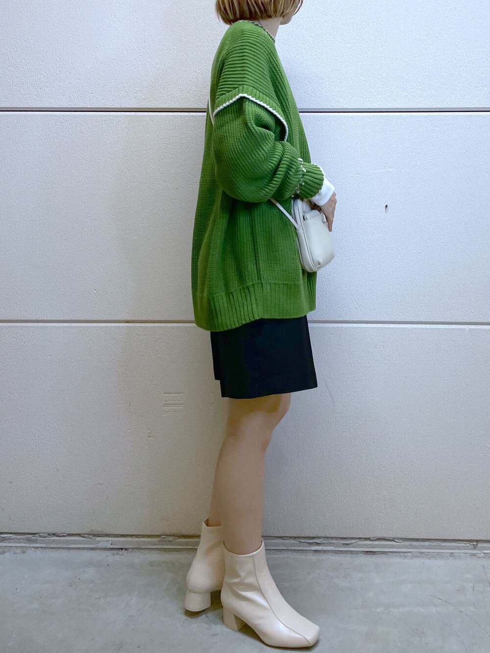 グリーン系のニット/セーター、ブラック系のパンツ、ホワイト系のTシャツ/カットソーを着用したレディースの秋コーディネートの2枚目の写真