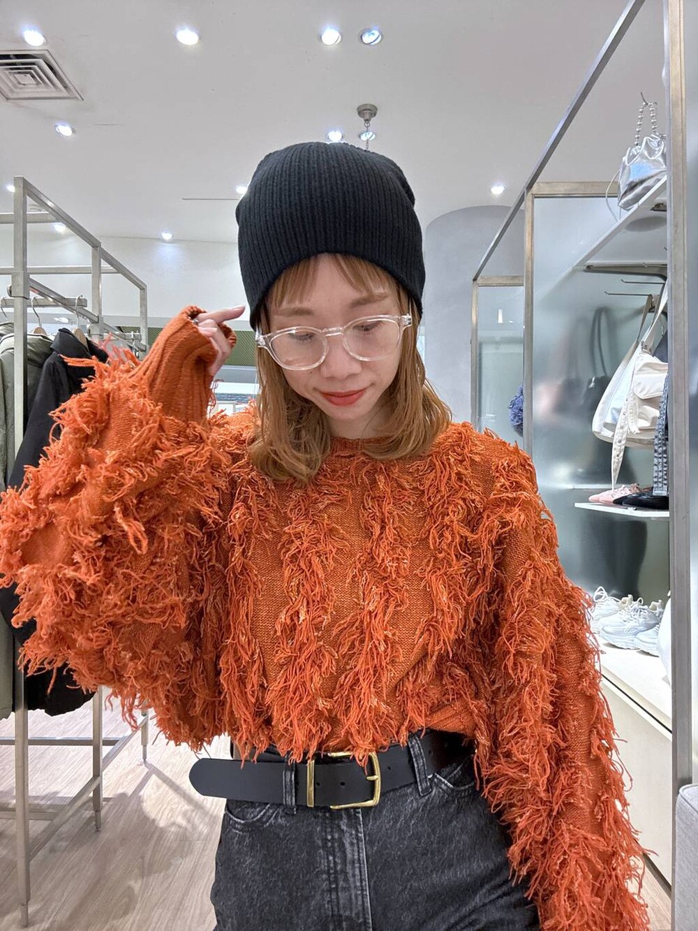 オレンジ系のカーディガン/ボレロ、ブラック系のスニーカー、ブラック系のベルトを着用したレディースの冬コーディネートの5枚目の写真