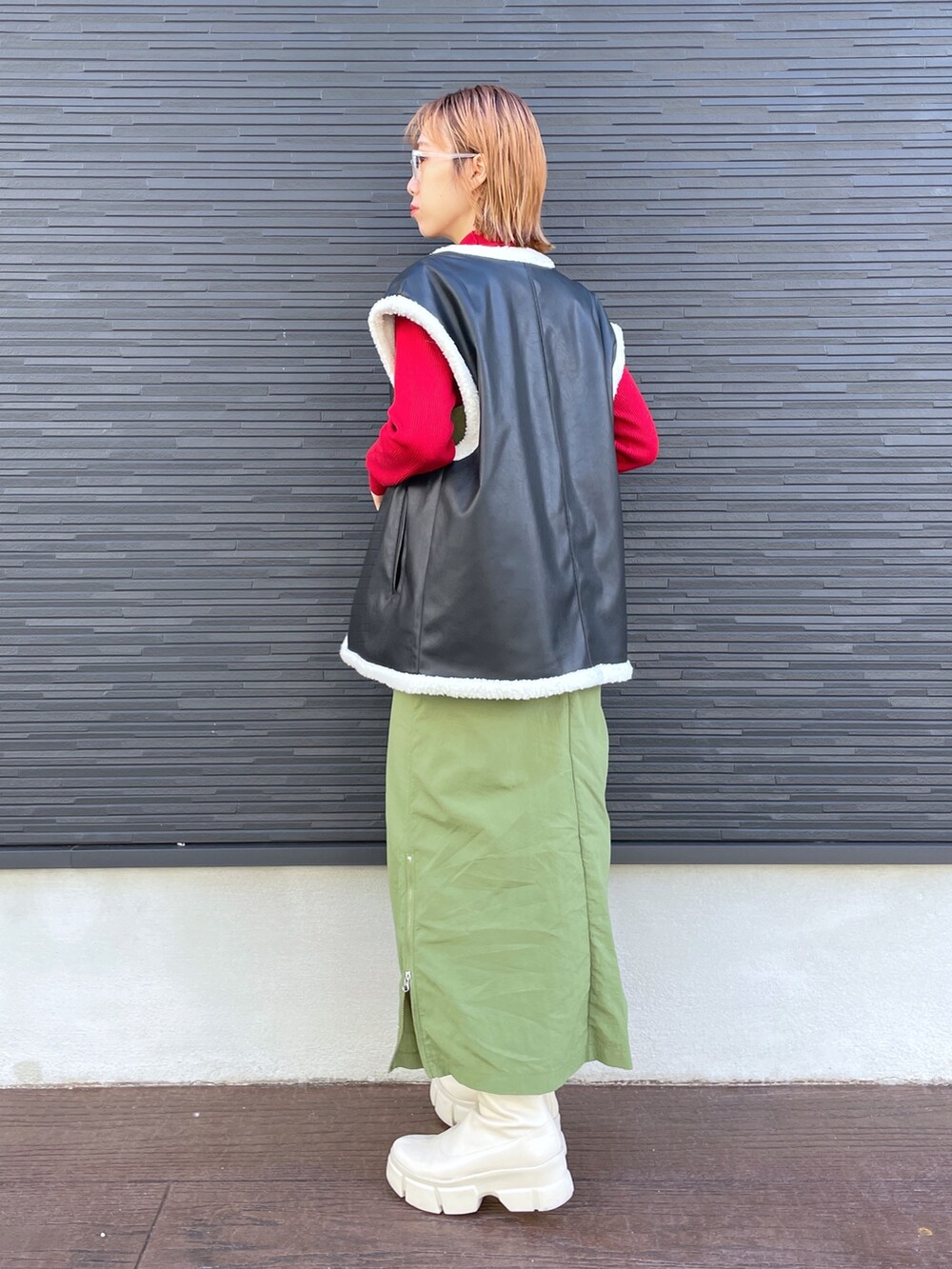 レッド系のニット/セーター、ブラック系のジャケット/アウター、ホワイト系のブーツを着用したレディースの冬コーディネートの3枚目の写真