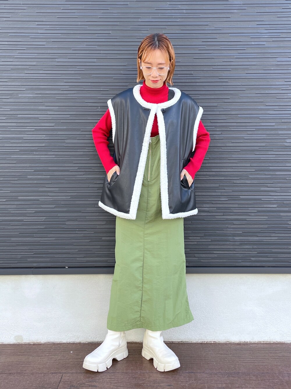 レッド系のニット/セーター、ブラック系のジャケット/アウター、ホワイト系のブーツを着用したレディースの冬コーディネートの2枚目の写真