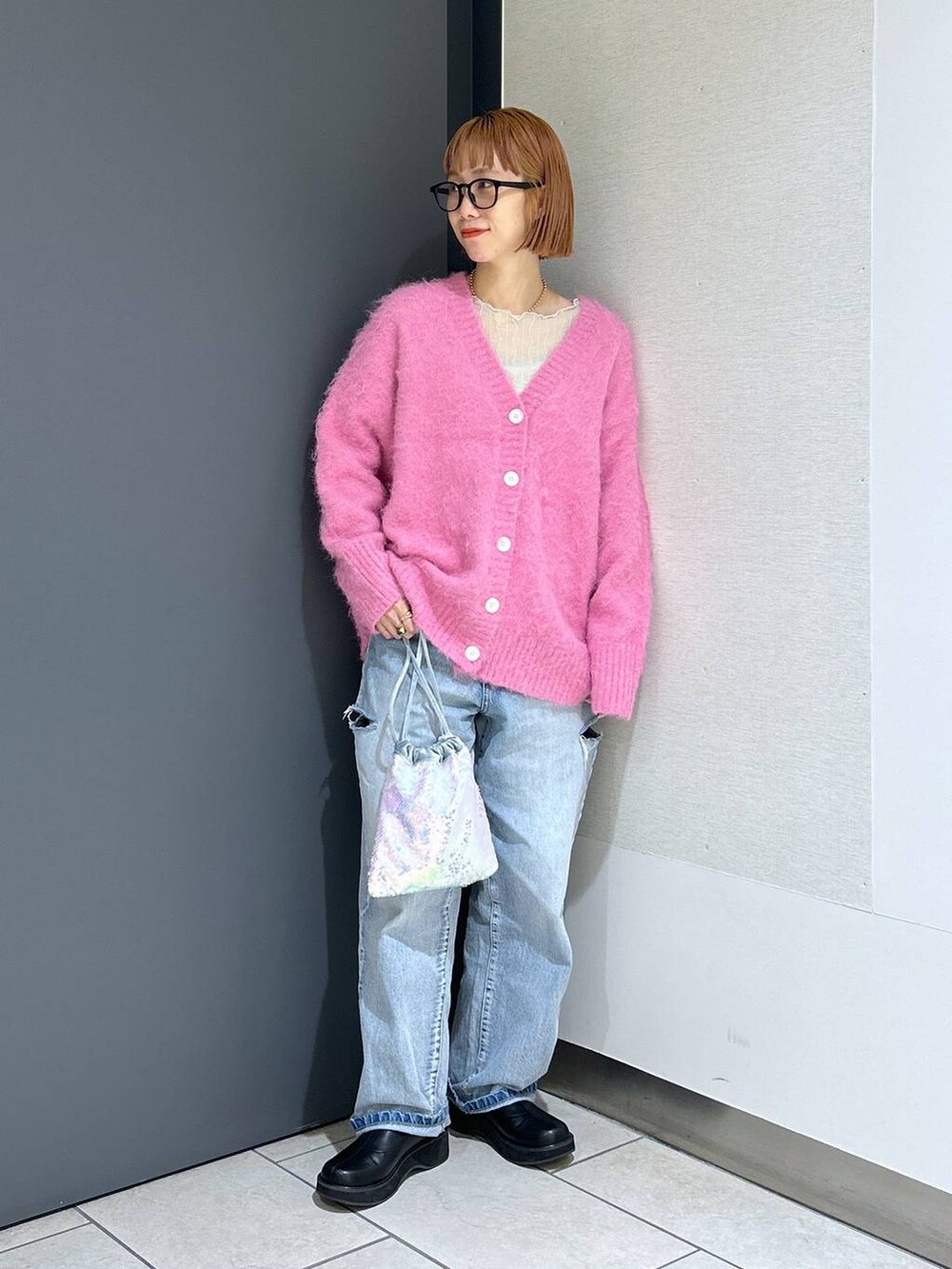 ブルー系のデニムパンツ、シルバー系のショルダーバッグ、ピンク系のカーディガン/ボレロを着用したレディースの冬コーディネートの9枚目の写真