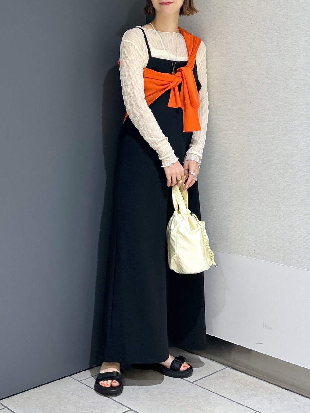 ブラック系のサンダル、オレンジ系のカーディガン/ボレロ、ホワイト系のTシャツ/カットソーを着用したレディースの春コーディネートの2枚目の写真