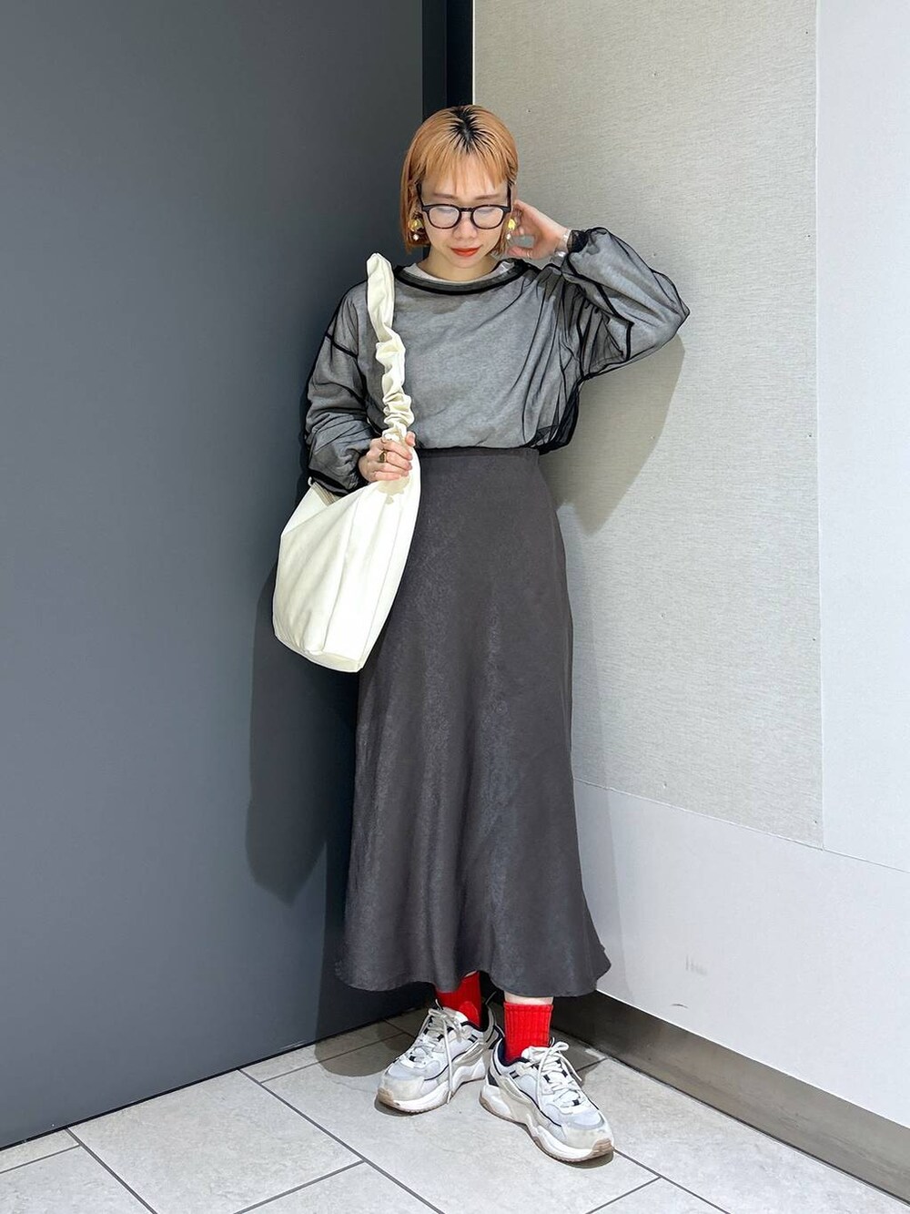 ベージュ系のトートバッグ、ブラック系のTシャツ/カットソー、グレー系のスカートを着用したレディースの春コーディネートの2枚目の写真