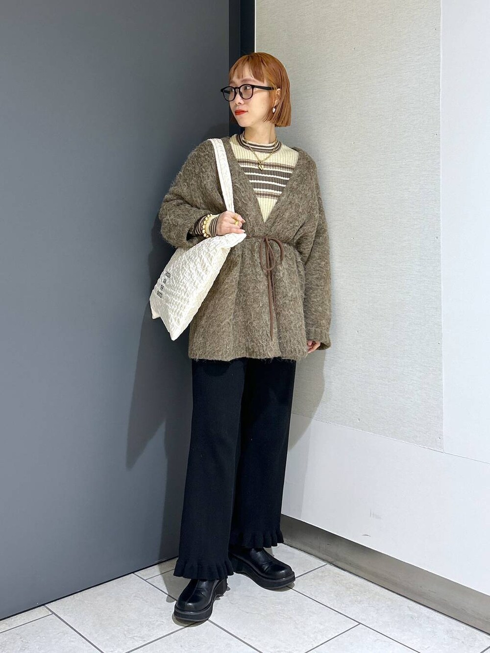 ホワイト系のトートバッグ、ブラック系のその他パンツ、ブラック系のブーツを着用したレディースの秋コーディネートの7枚目の写真