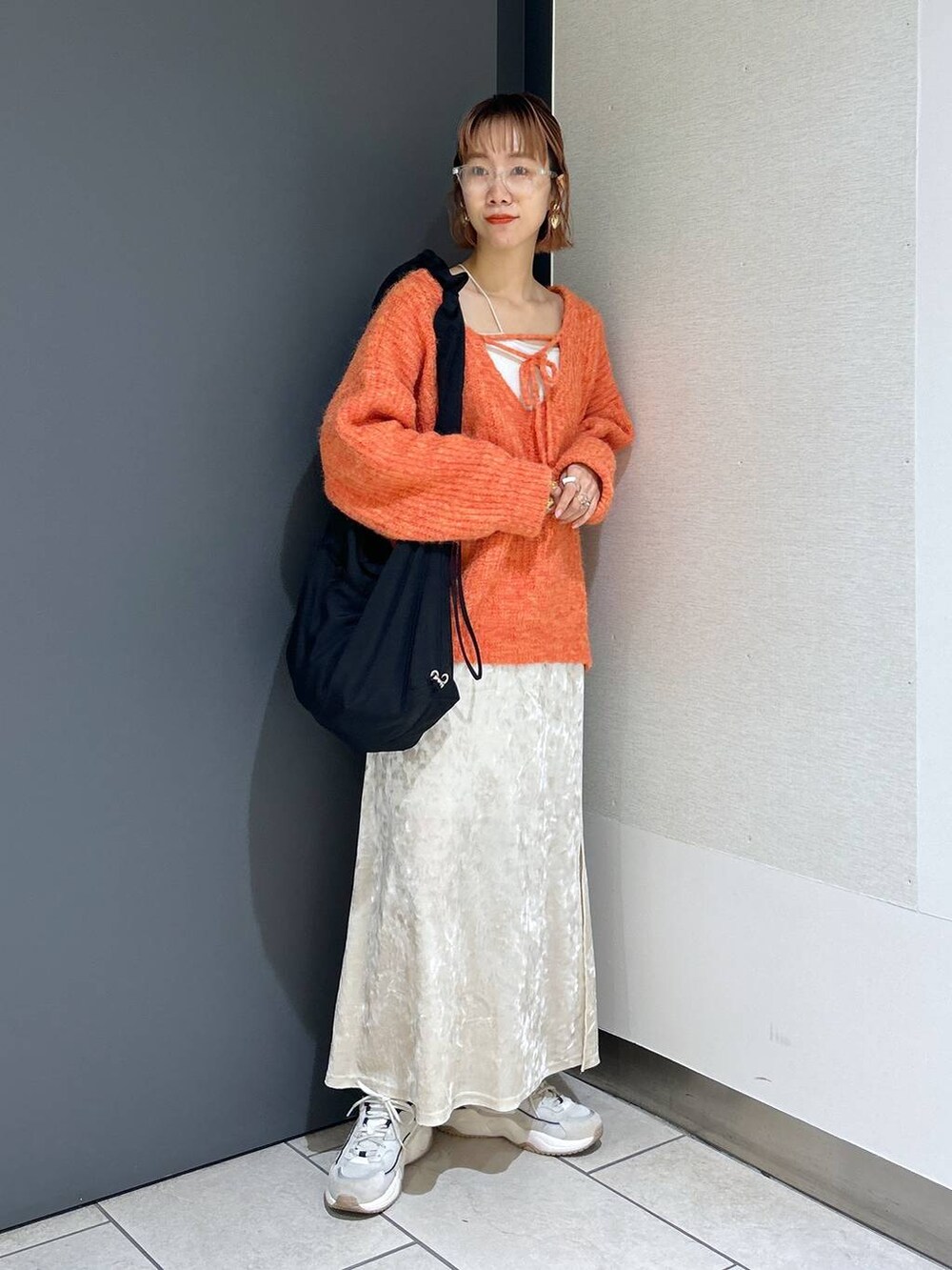ホワイト系のタンクトップ、オレンジ系のニット/セーター、ホワイト系のスカートを着用したレディースの秋コーディネートの7枚目の写真