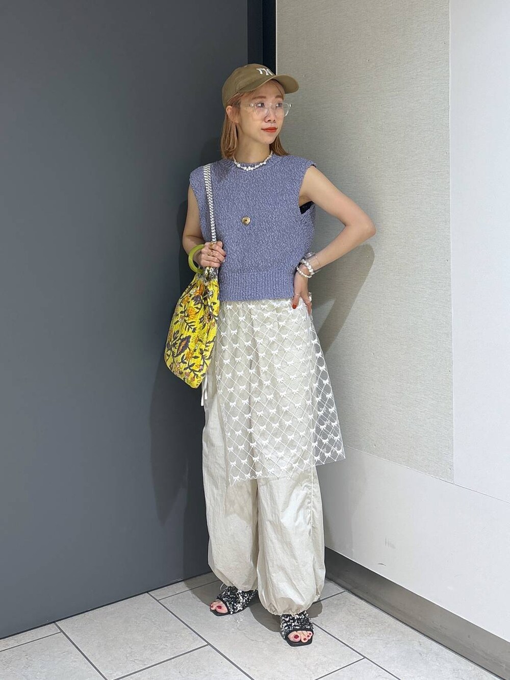 イエロー系のトートバッグ、シルバー系のサンダル、ホワイト系のその他パンツを着用したレディースの夏コーディネートの8枚目の写真