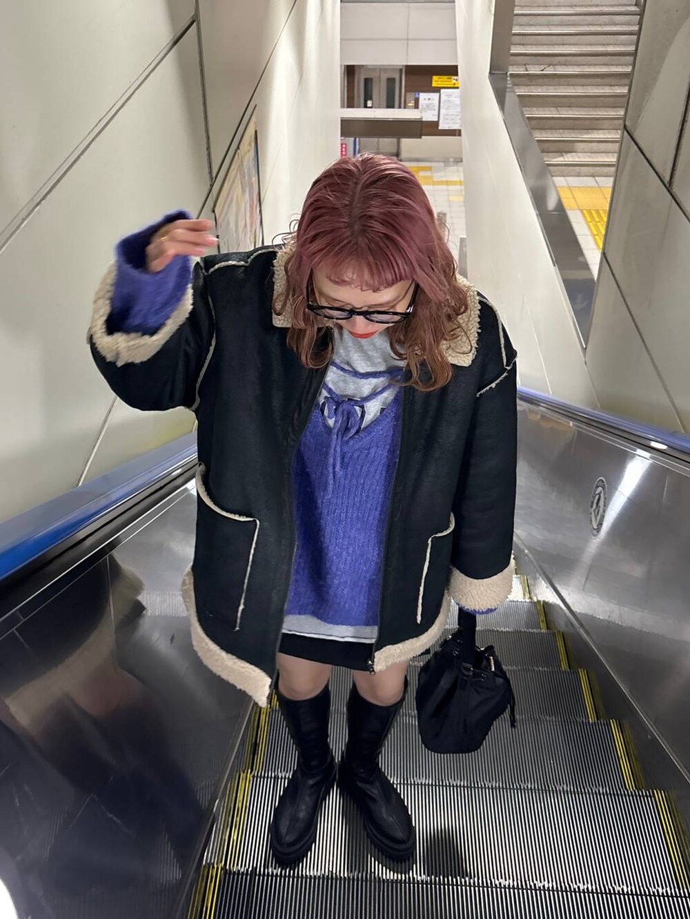 ブラック系のブルゾン、ブラック系のブーツ、ブラック系のショルダーバッグを着用したレディースの冬コーディネートの4枚目の写真