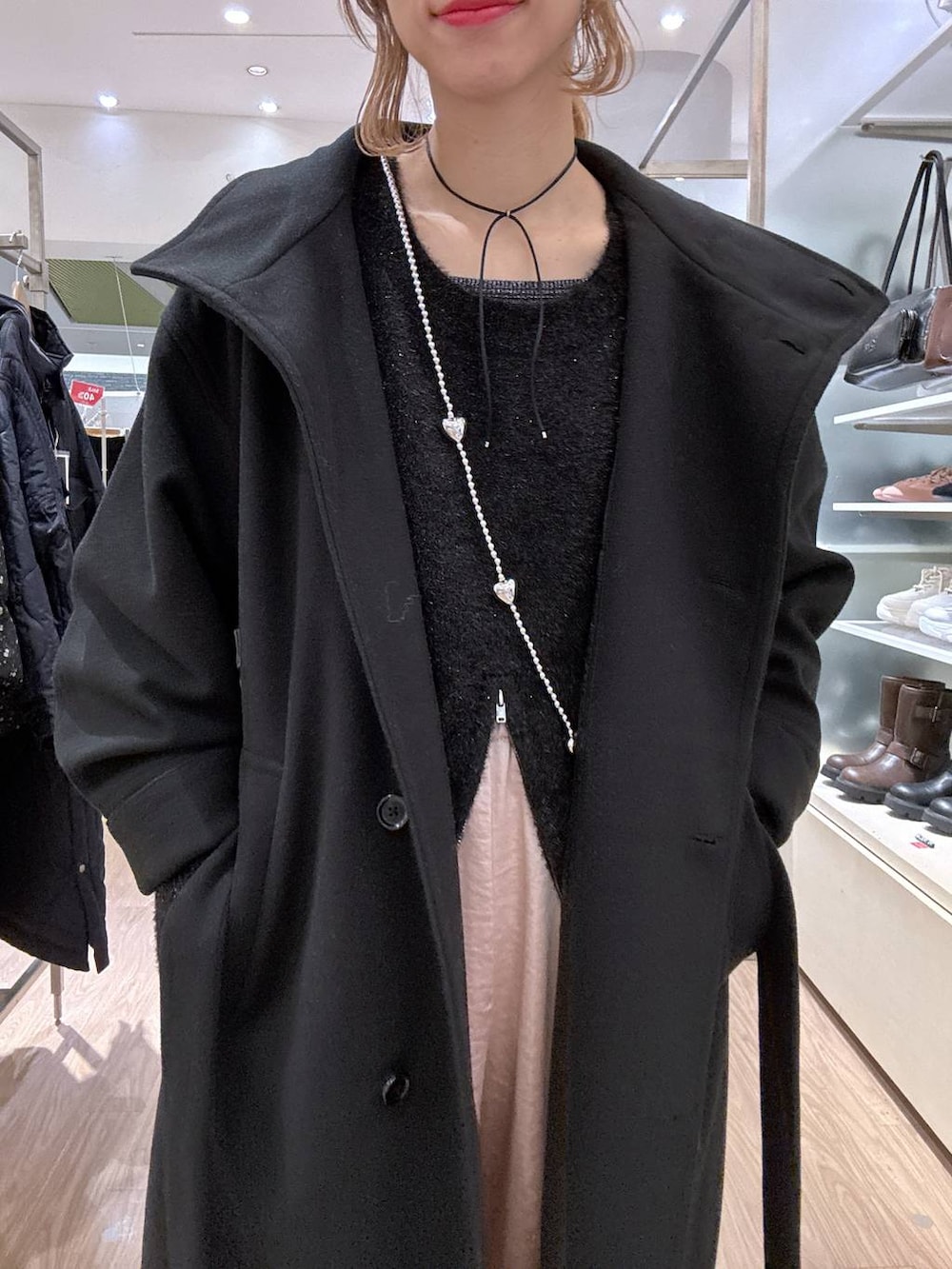 ブラック系のステンカラーコート、ピンク系のカーゴパンツ、ブラック系のニット/セーターを着用したレディースの冬コーディネートの4枚目の写真