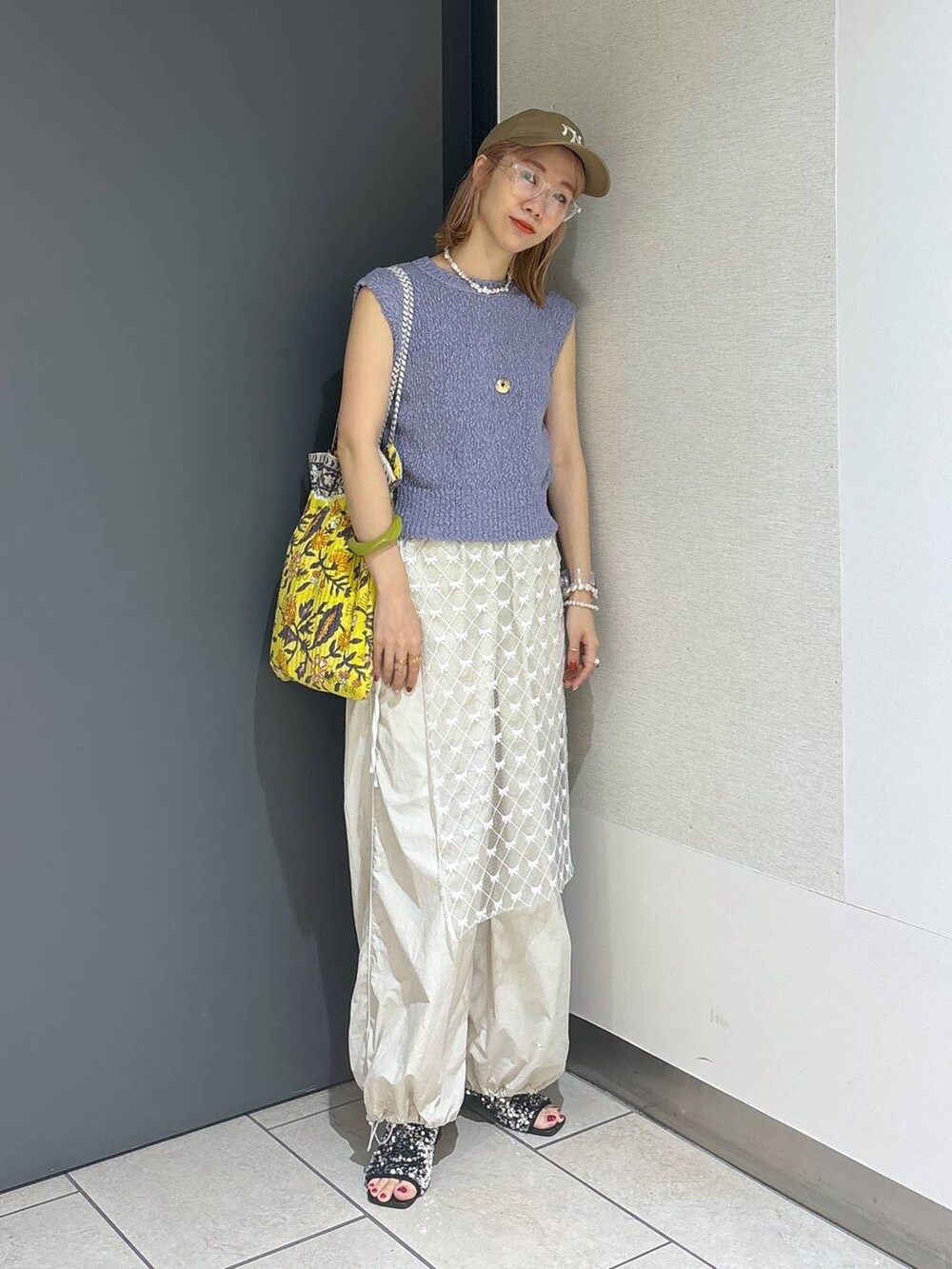 イエロー系のトートバッグ、シルバー系のサンダル、ホワイト系のその他パンツを着用したレディースの夏コーディネートの2枚目の写真