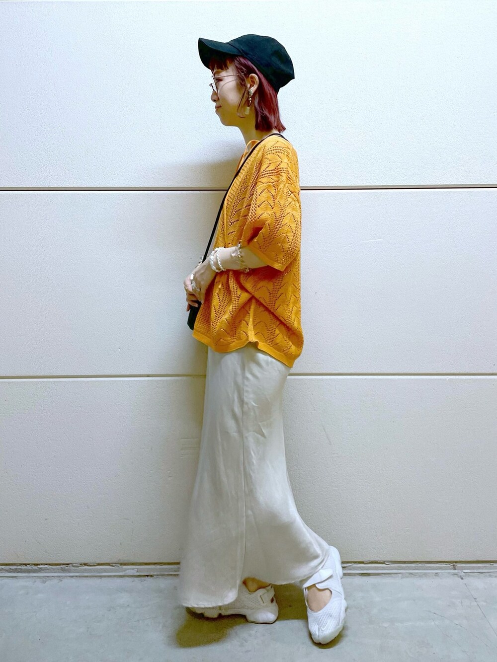 ブラック系のTシャツ/カットソー、オレンジ系のニット/セーター、ブラック系のスカートを着用したレディースの春コーディネートの3枚目の写真