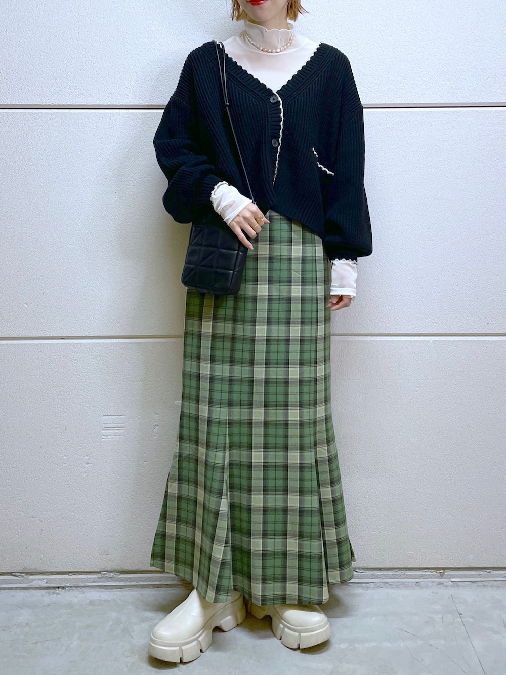 ブラック系のカーディガン/ボレロ、ホワイト系のトップス、グリーン系のスカートを着用したレディースの秋コーディネートの5枚目の写真