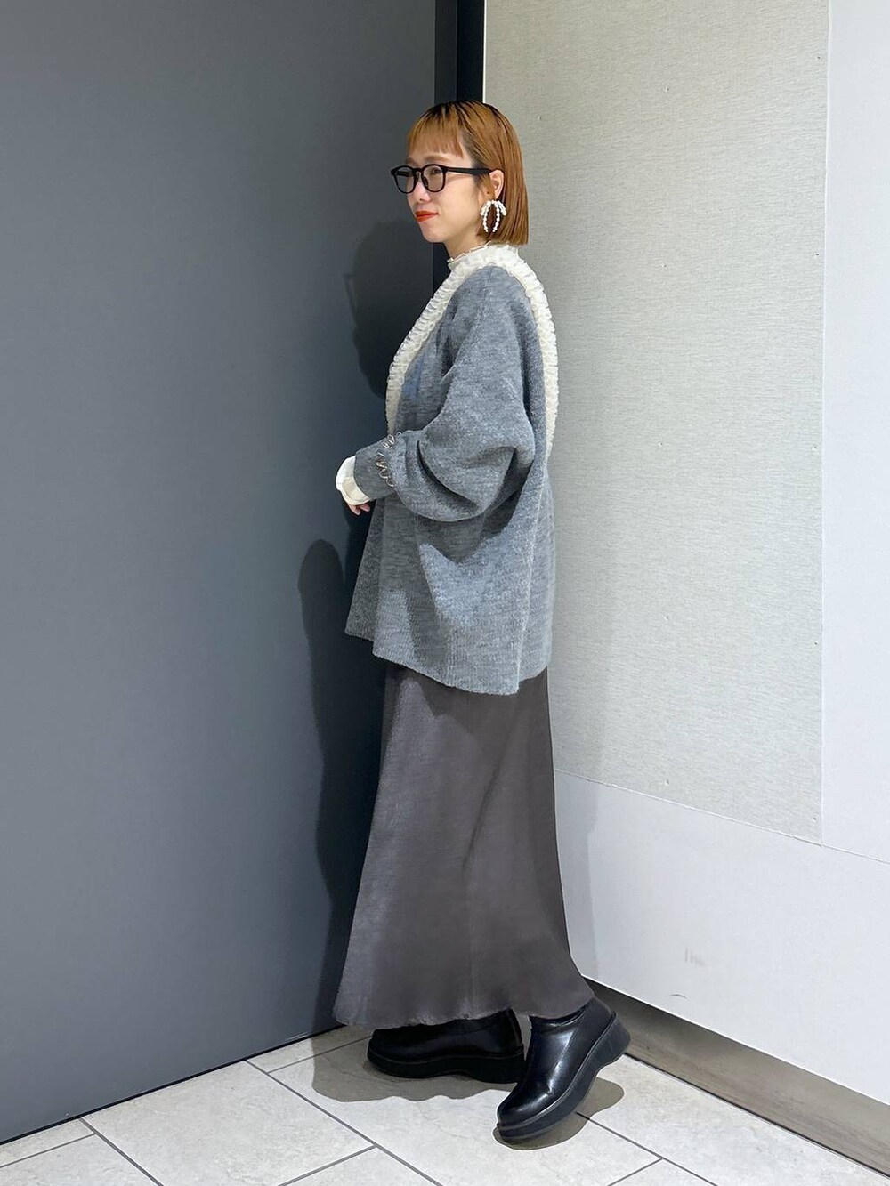 グレー系のニット/セーター、ホワイト系のTシャツ/カットソー、ブラック系のブーツを着用したレディースの冬コーディネートの2枚目の写真