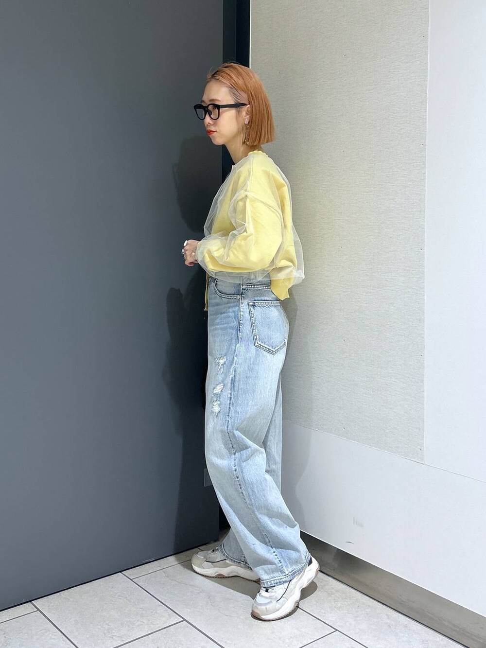 ブラック系のハンドバッグ、イエロー系のニット/セーター、ブラック系のTシャツ/カットソーを着用したレディースの春コーディネートの5枚目の写真