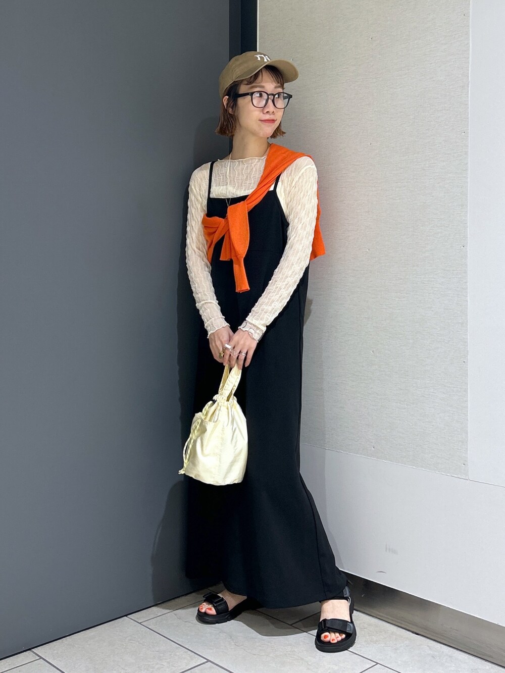 ブラック系のサンダル、オレンジ系のカーディガン/ボレロ、ホワイト系のTシャツ/カットソーを着用したレディースの春コーディネートの5枚目の写真