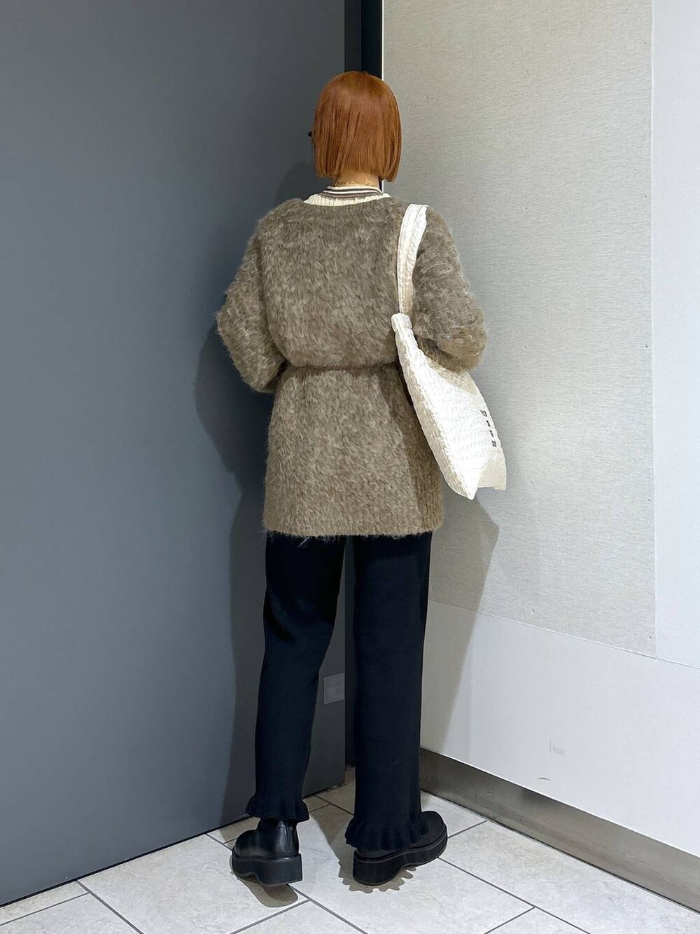 ホワイト系のトートバッグ、ブラック系のその他パンツ、ブラック系のブーツを着用したレディースの秋コーディネートの5枚目の写真