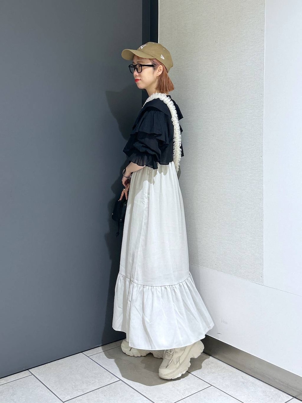 ホワイト系のワンピース、ホワイト系のスニーカー、ブラック系のショルダーバッグを着用したレディースの春コーディネートの3枚目の写真