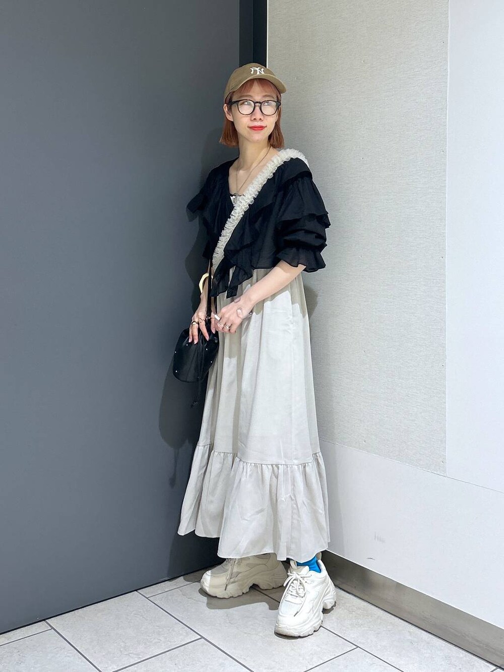 ホワイト系のワンピース、ホワイト系のスニーカー、ブラック系のショルダーバッグを着用したレディースの春コーディネートの6枚目の写真