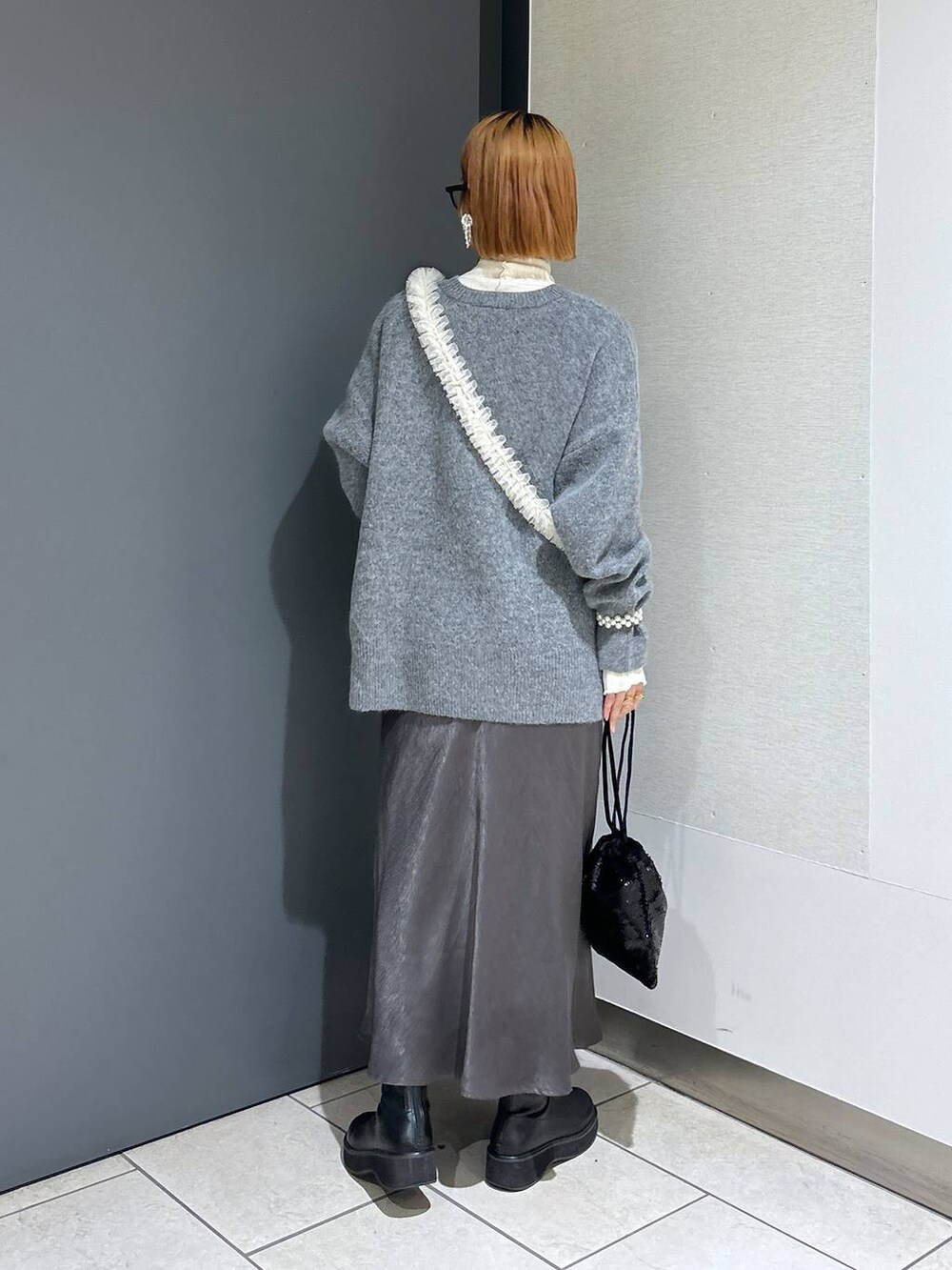 グレー系のニット/セーター、ホワイト系のTシャツ/カットソー、ブラック系のブーツを着用したレディースの冬コーディネートの3枚目の写真