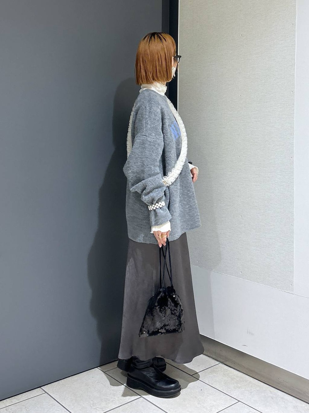 グレー系のニット/セーター、ホワイト系のTシャツ/カットソー、ブラック系のブーツを着用したレディースの冬コーディネートの4枚目の写真