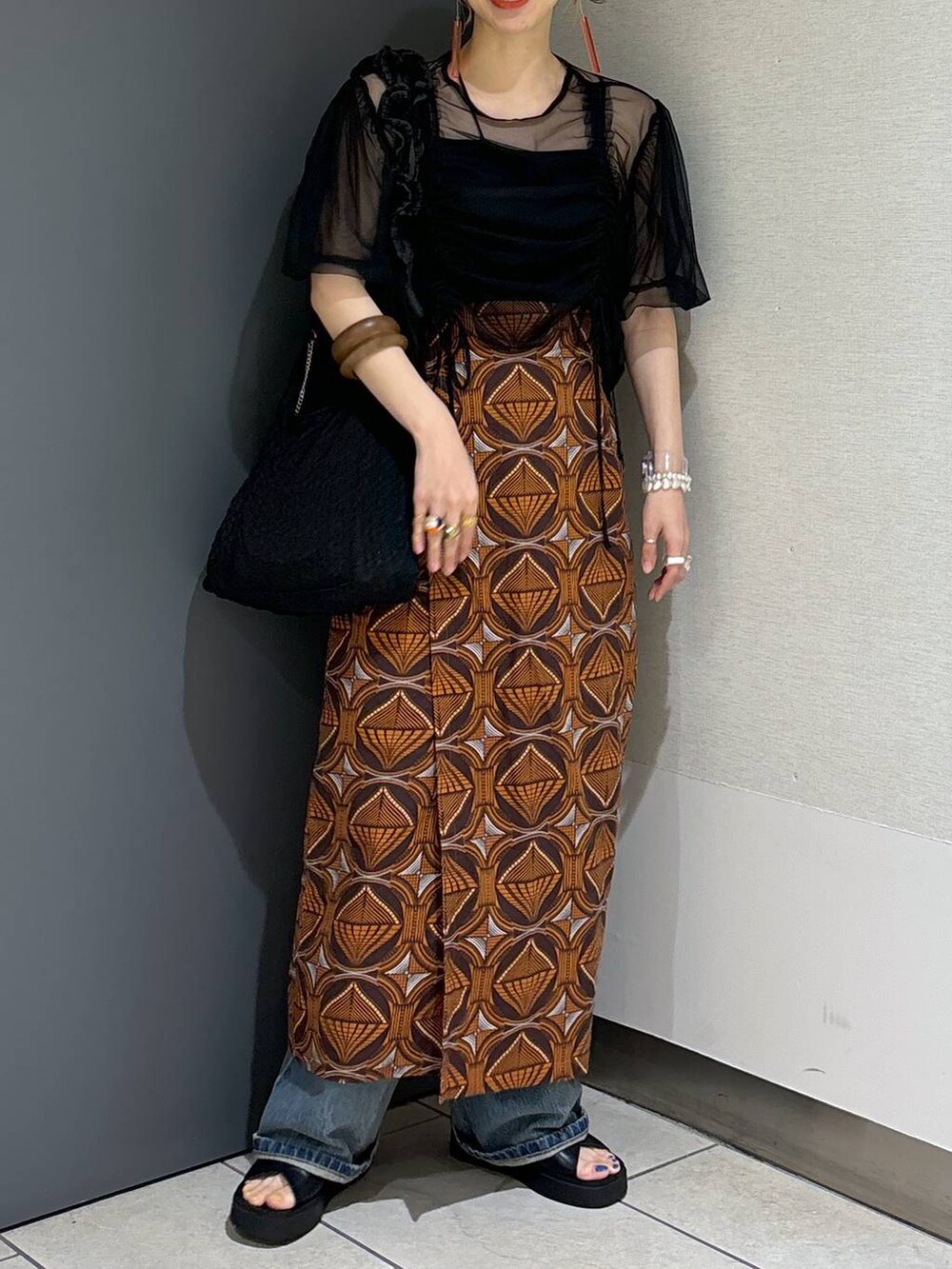 ブラック系のトートバッグ、ブラウン系のスカート、ブラック系のサンダルを着用したレディースの春コーディネートの6枚目の写真