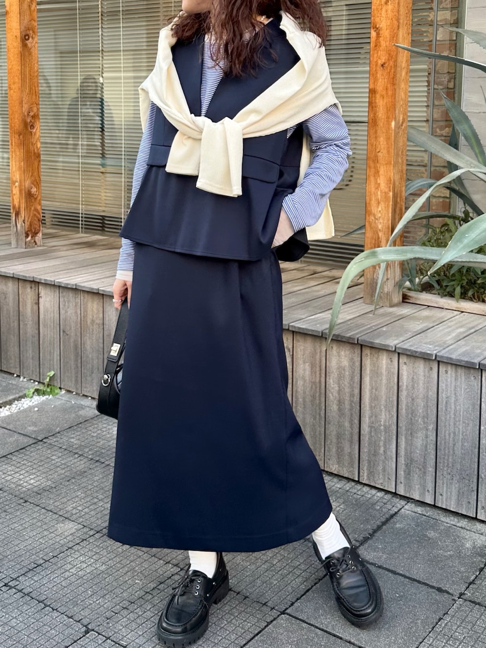 ブルー系のTシャツ/カットソー、ホワイト系のカーディガン/ボレロ、ブルー系のジャンパースカートを着用したレディースの春コーディネートの2枚目の写真