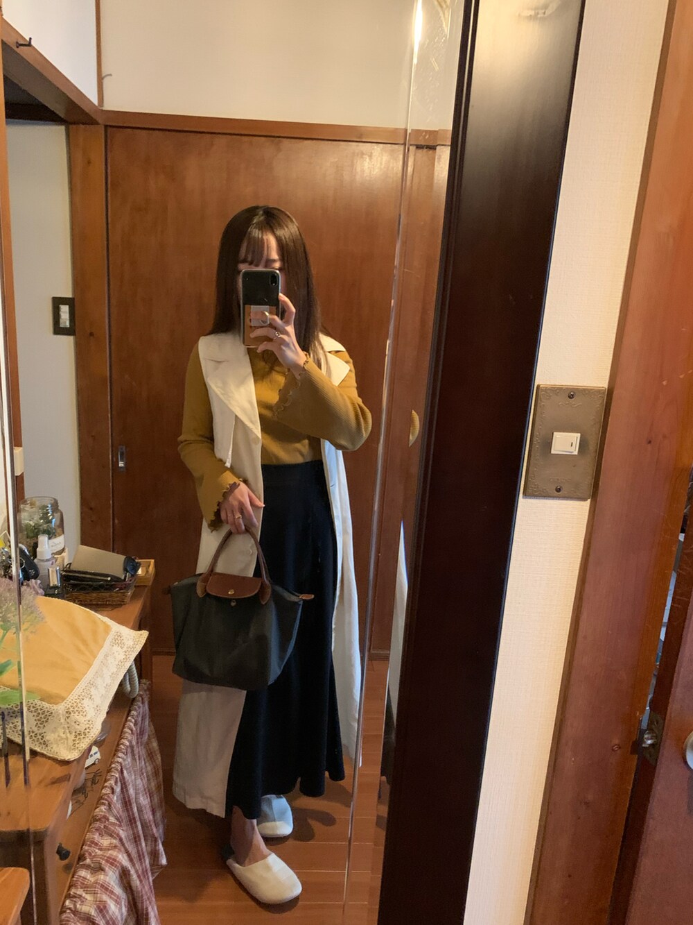 グレー系のトートバッグ、ベージュ系のトレンチコート、ブラック系のスカートを着用したレディースの秋コーディネートの2枚目の写真