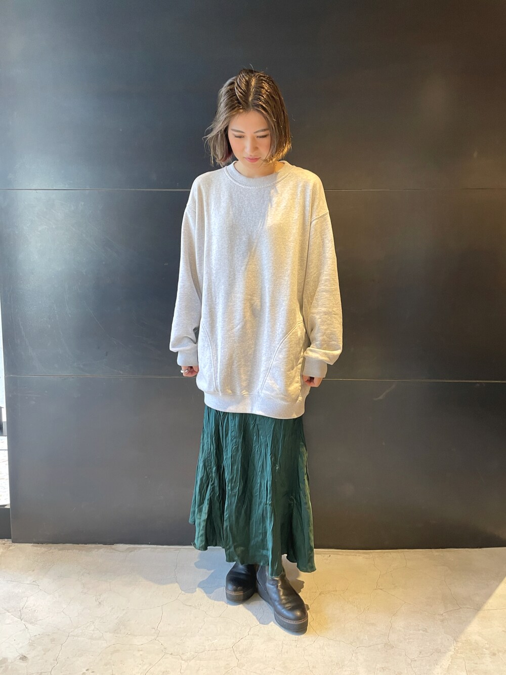 グレー系のニット/セーター、グリーン系のスカートを着用したレディースの冬コーディネートの2枚目の写真