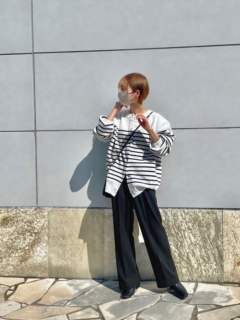 ホワイト系のカーディガン/ボレロ、ブラック系のパンツ、ブラック系のブーツを着用したレディースの秋コーディネートの2枚目の写真