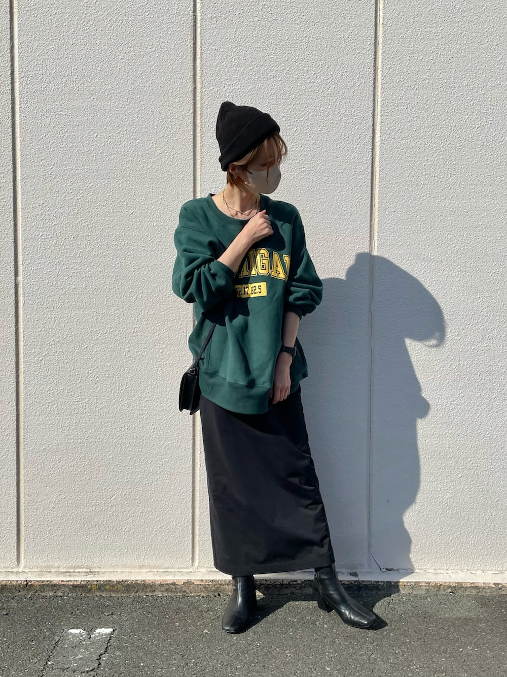 グリーン系のスウェット、ブラック系のスカート、ブラック系のブーツを着用したレディースの秋コーディネートの2枚目の写真