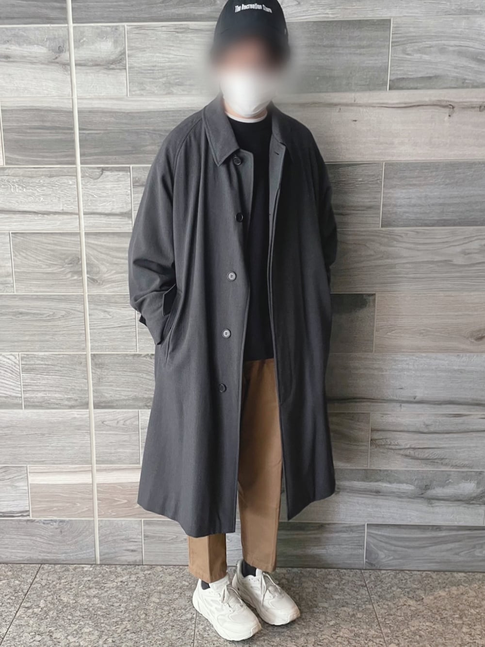 グレー系のステンカラーコート、ブラック系のスウェット、ベージュ系のその他パンツを着用したメンズの冬コーディネートの2枚目の写真