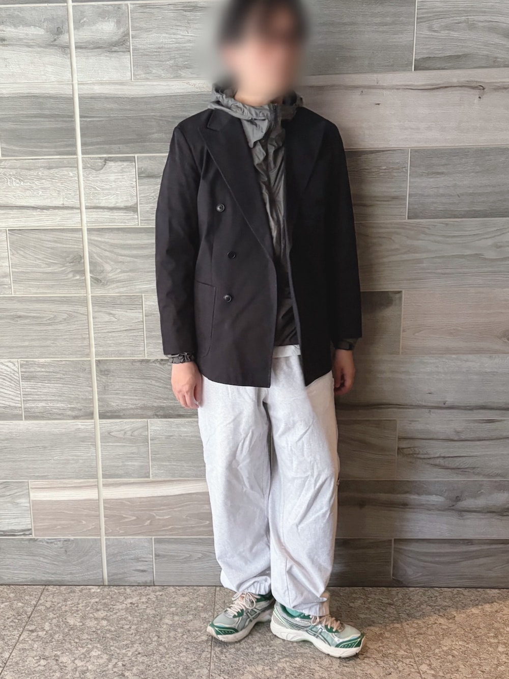 ブラック系のテーラードジャケット、グリーン系のナイロンジャケット、グレー系のスウェットパンツを着用したメンズの春コーディネートの2枚目の写真