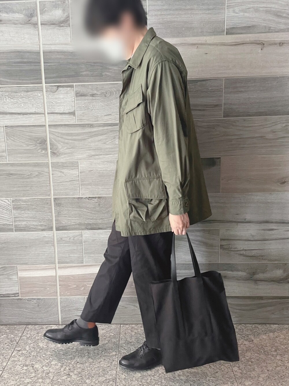 グリーン系のミリタリージャケット、ブラック系のスラックス、ブラック系のシューズを着用したメンズの秋コーディネートの2枚目の写真